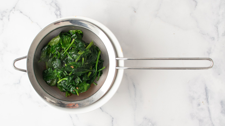 cooked spinach in a strainer