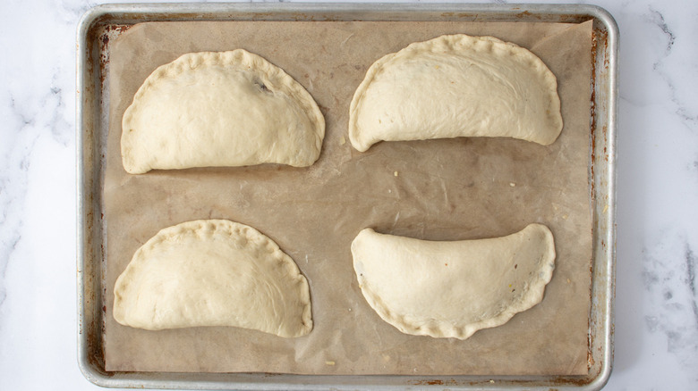 unbaked calzones on brown paper