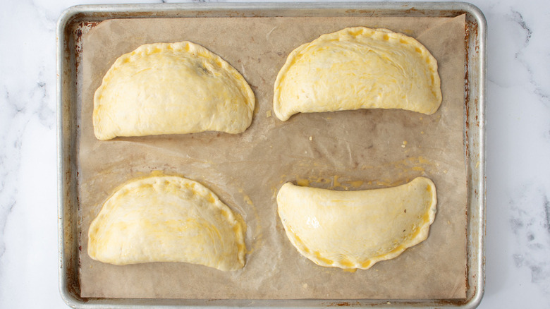 unbaked calzones on brown paper