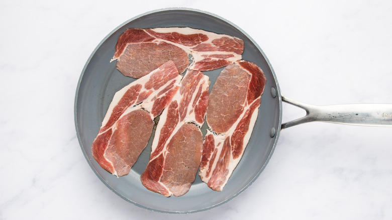 Strips of bacon in frying pan