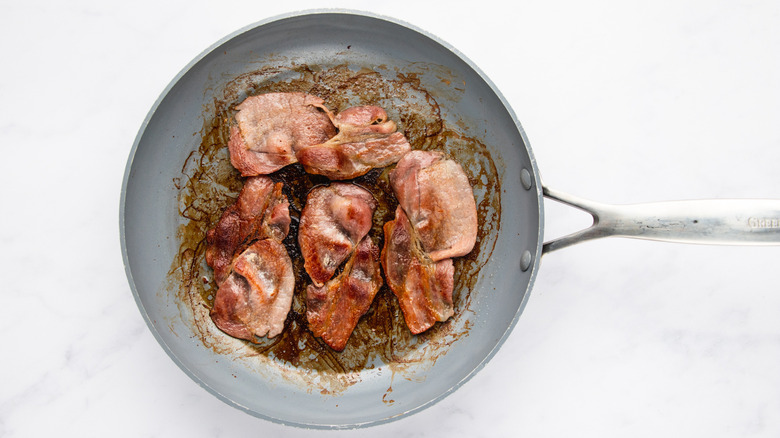 Cooked bacon strips in frying pan