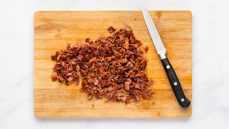 Chopped cooked bacon on wooden cutting board