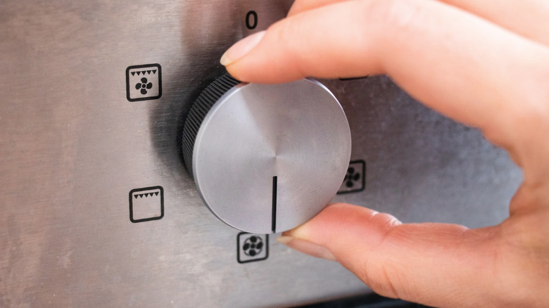 Hand turning dial on oven