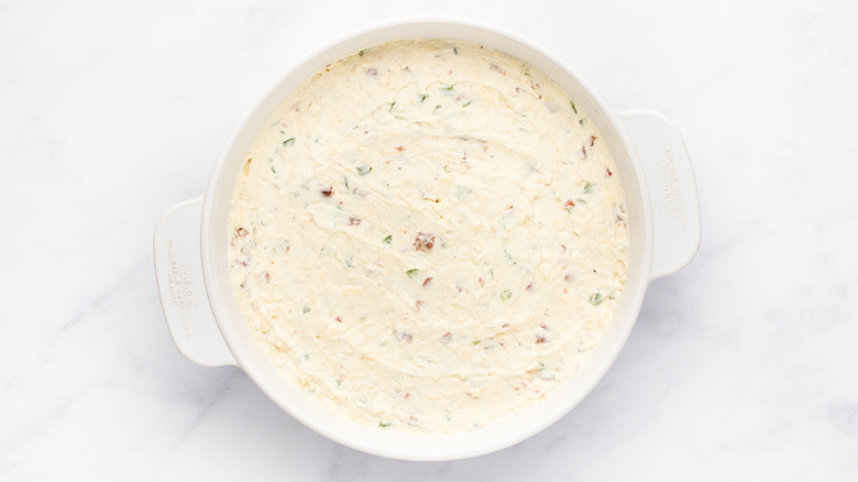 Cheesy bacon jalapeño dip mixture in white dish