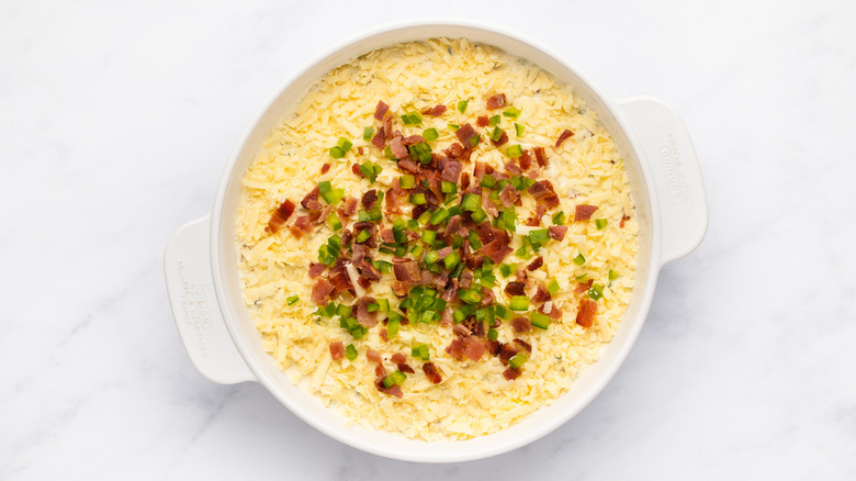 Unbaked cheesy bacon jalapeño dip in white dish