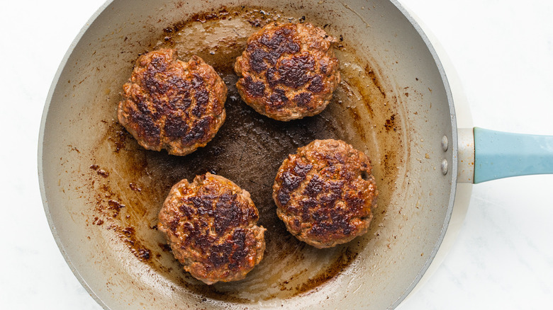 burger patties cooking in skillet