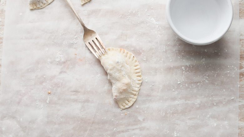 pepperoni pizza empanadas being closed with a fork