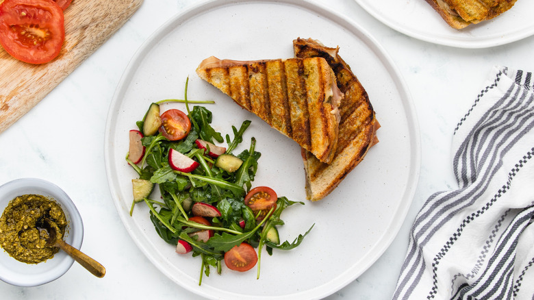 Cheesy prosciutto panini on plate with salad