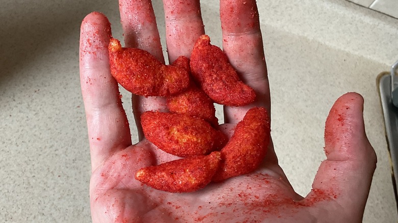 Cheetos in hand covered by flavor dusting