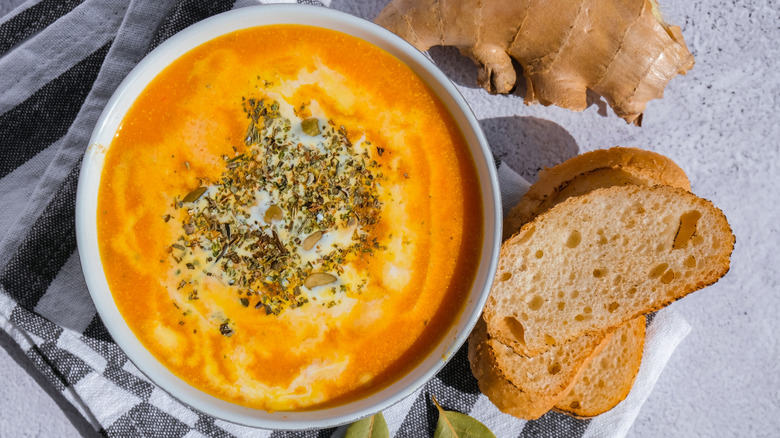 Bowl of creamy vegetable soup with bread and raw ginger