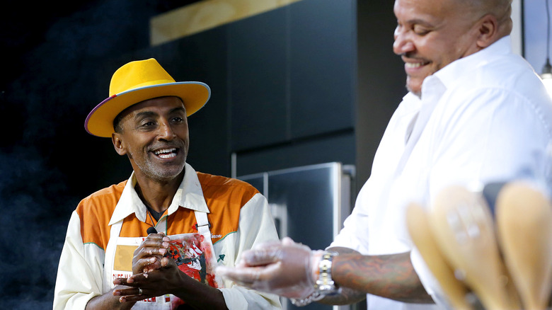 Chef marcus samuelsson cooking in kitchen in yellow hat