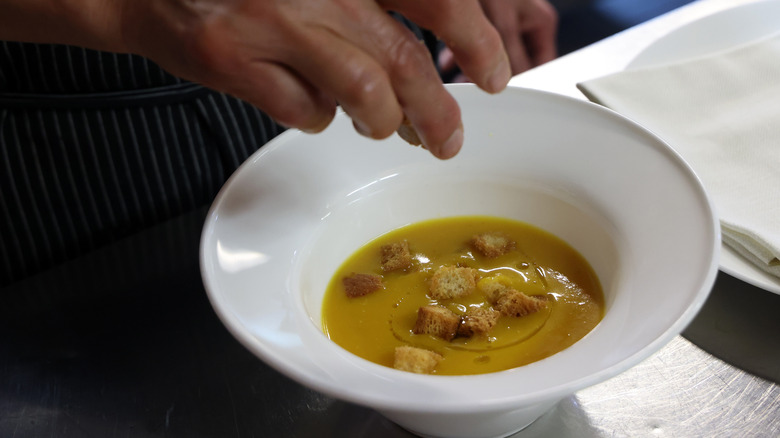 chef adding finishing touches to soup