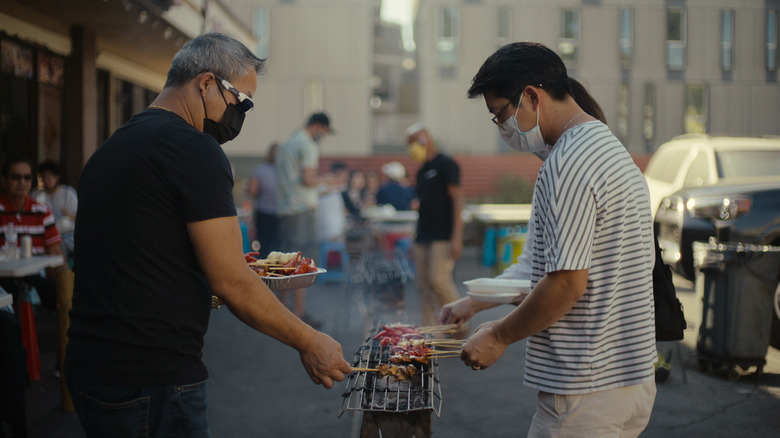 Two men roasting meat at a grill