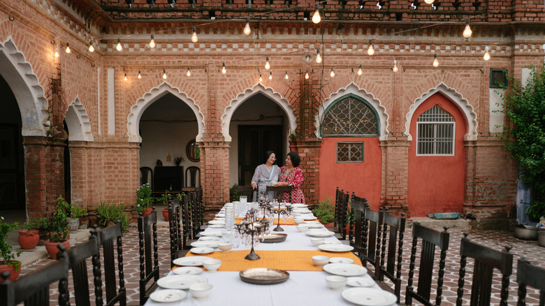 Still from "Chef's Table": a long outdoor dining table in a courtyard with two women at the head of the table