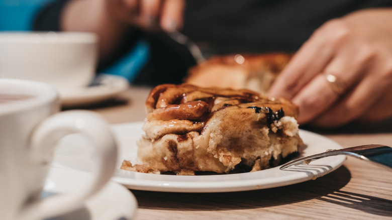 person cutting into Chelsea bun