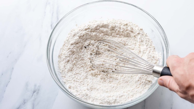 hand whisking flour in bowl 