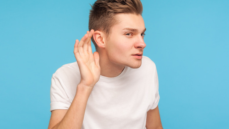 man listening, cupping ear, can't hear