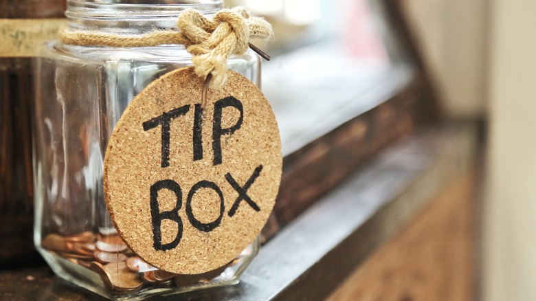 Closeup of glass tip jar with some coins