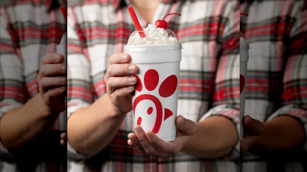 Man in flannel holding out Chick-fil-A's peppermint chip milkshake