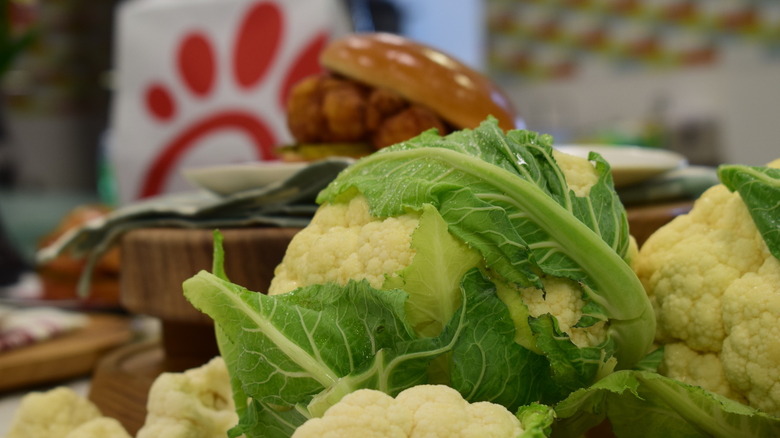 Chick-fil-A cauliflower sandwich behind heads of cauliflower