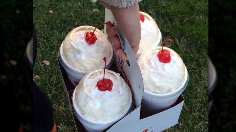 Person carrying a drink holder with four Chick-fil-A milkshakes in it