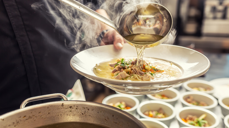 ladling chicken soup into a bowl. 