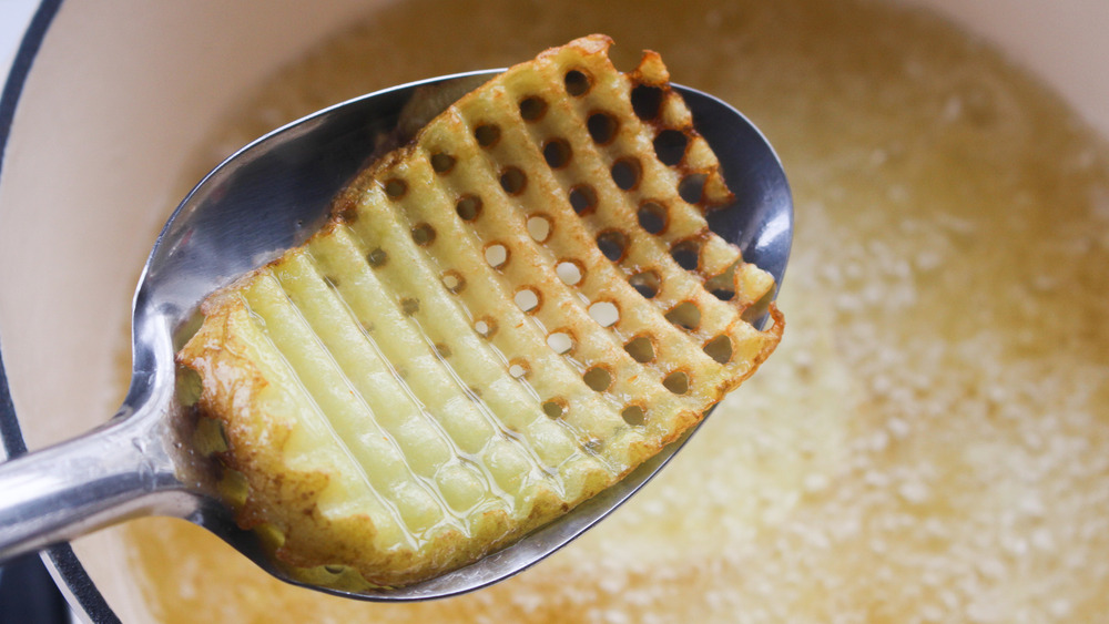 A waffle cut potato slice dripping oil