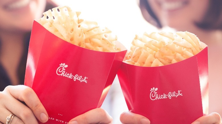 Two people holding containers of Chick-fil-a fries