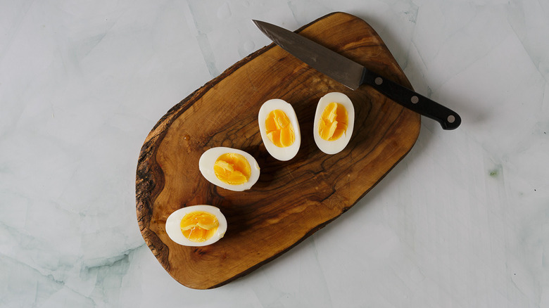 four eggs on wooden cutting board