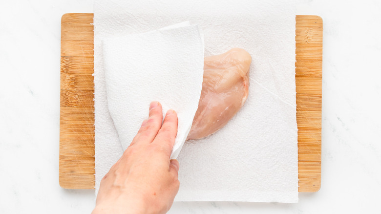 patting chicken breast dry with kitchen paper