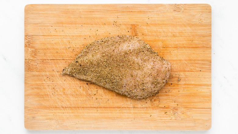 herb-coated chicken breast on cutting board