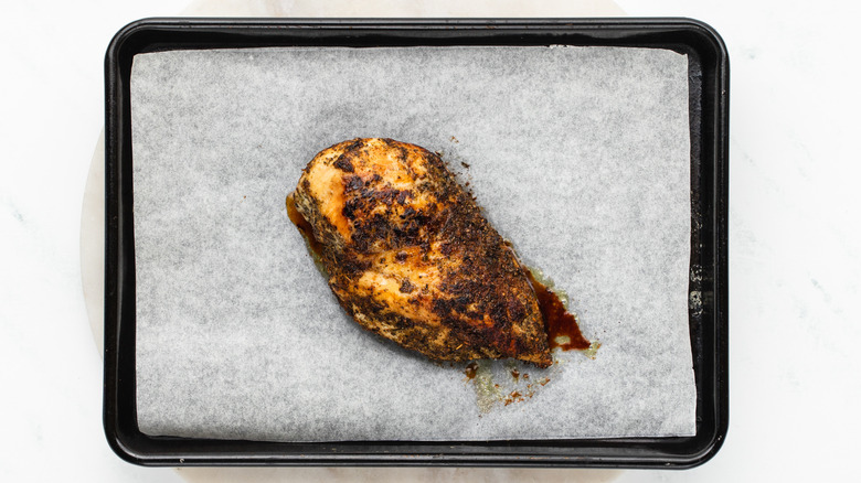 herby chicken breast on baking sheet