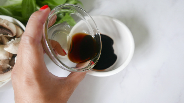 hand pouring sauce into bowl