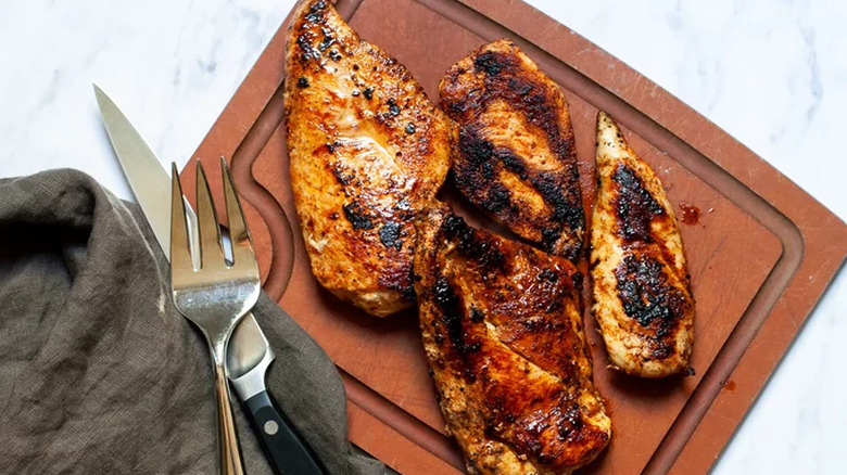 Charred chicken breast meat on board