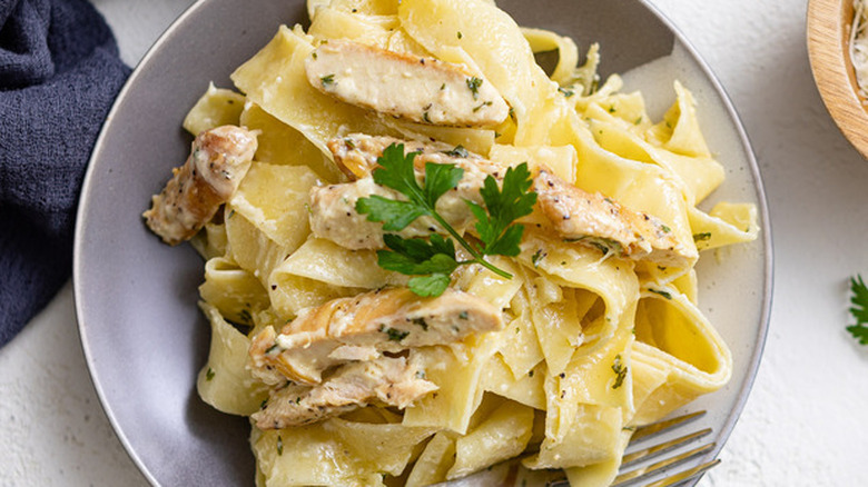 Bowl with wide noodles and sliced chicken