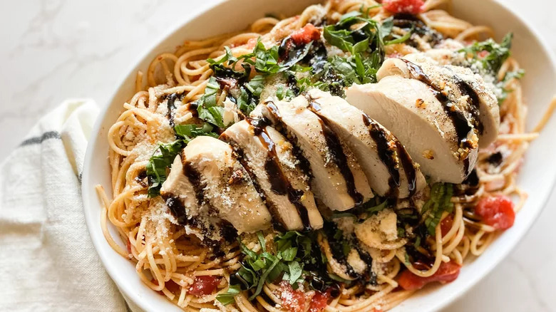 Sliced chicken breast with pasta and basil.