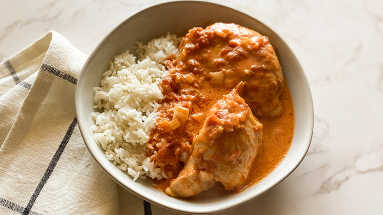 Butter chicken and sauce with rice in bowl