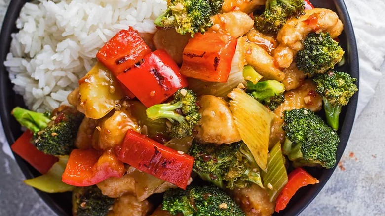 Black plate of chicken, rice, and veggies