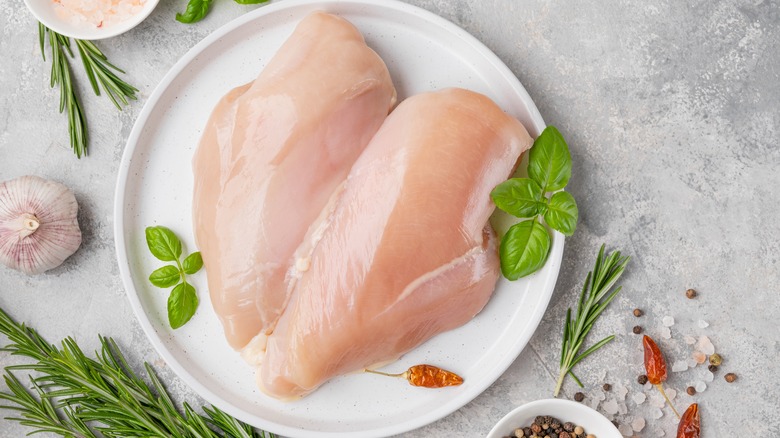 Raw chicken breasts on white plate