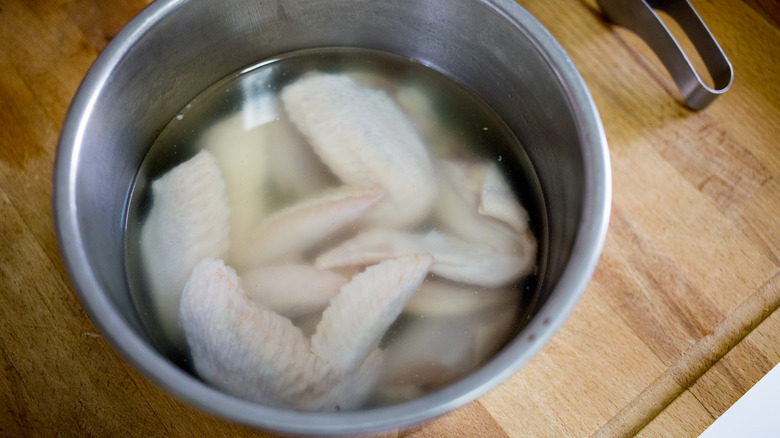 raw chicken wings in liquid