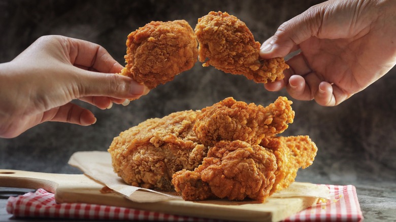 hands holding fried chicken wings 