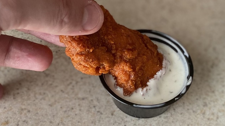 Hand dipping Nashville hot chicken crisper in ranch