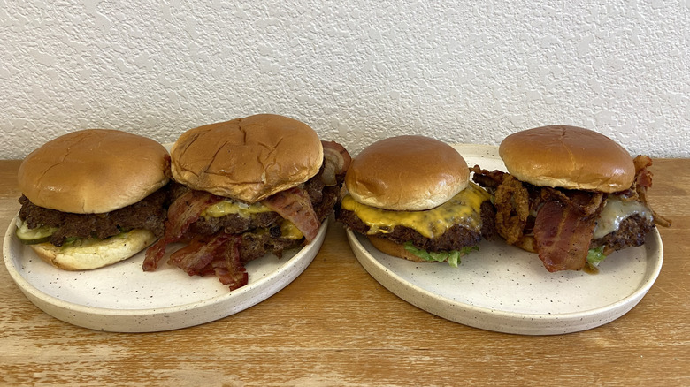 Four burgers are displayed on two plates