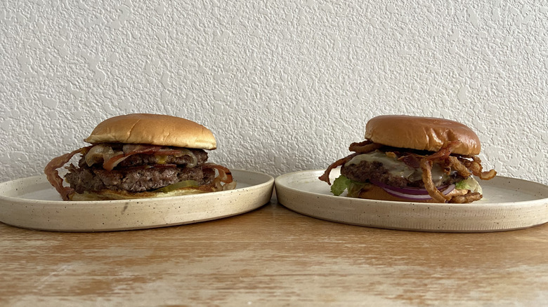 Two bacon burgers sit on separate plates