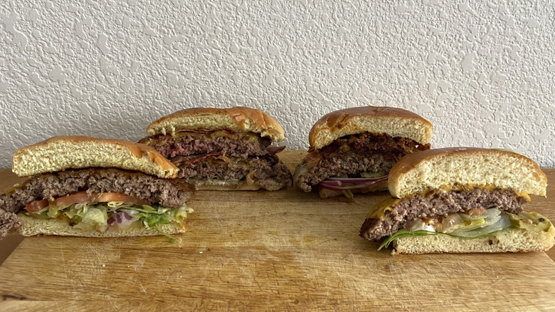 Four burger halves are displayed on a cutting board