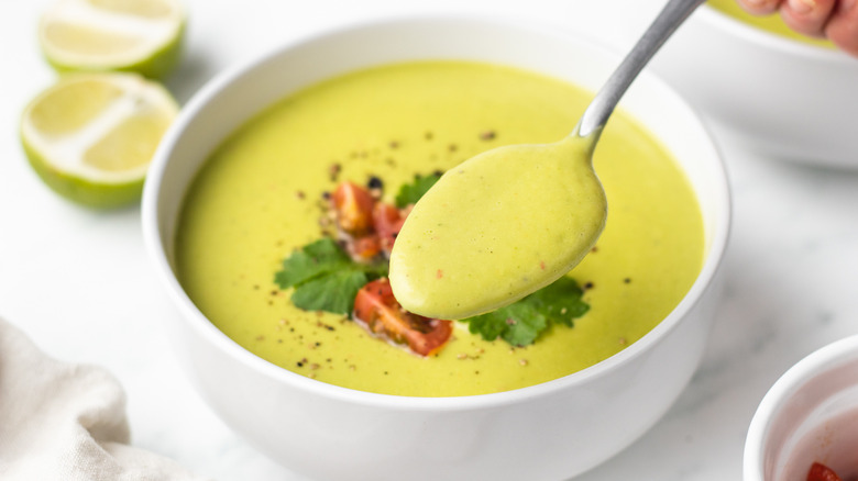 spooning avocado soup  out of bowl