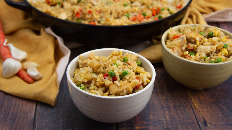 chicken fried rice in white bowls on wooden surface