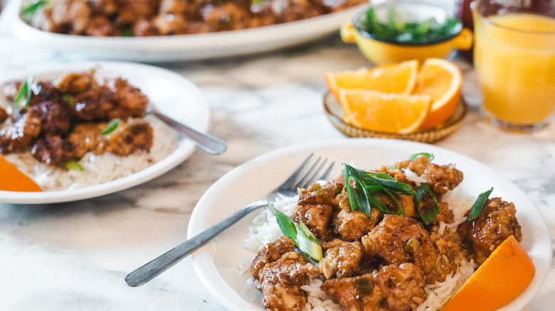 orange chicken on white plate with orange slices