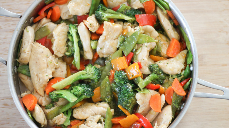 chicken stir fry in metal pot on wooden counter