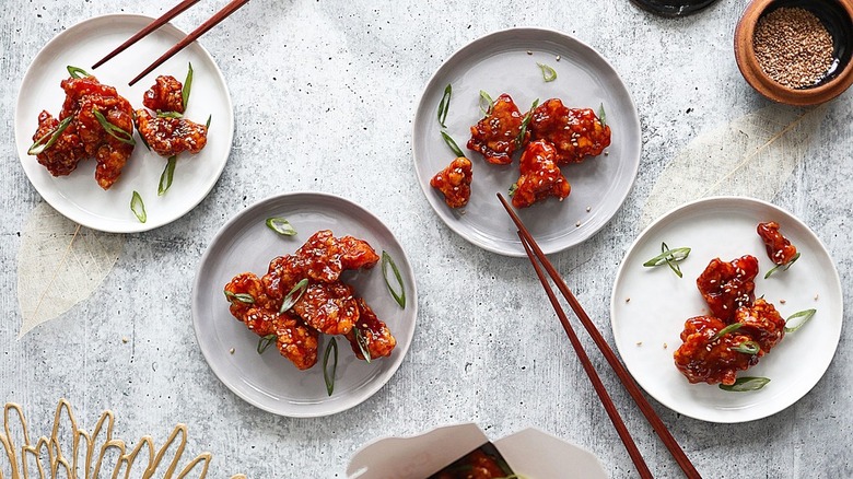 sesame chicken on white plates with chopsticks